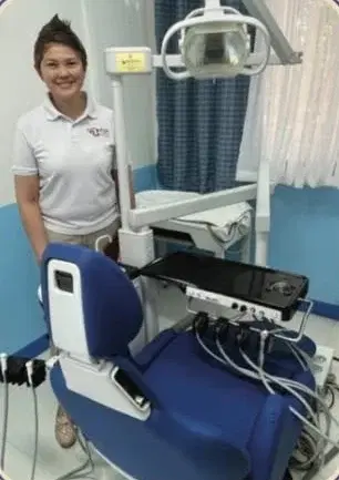 A dentist standing beside a dental chair in the rehabilitated clinic