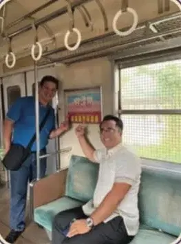 Two dentists beside an oral health slogan poster on a commuter train